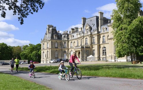 personnes en vélo circulant devant le chateau de Laversine